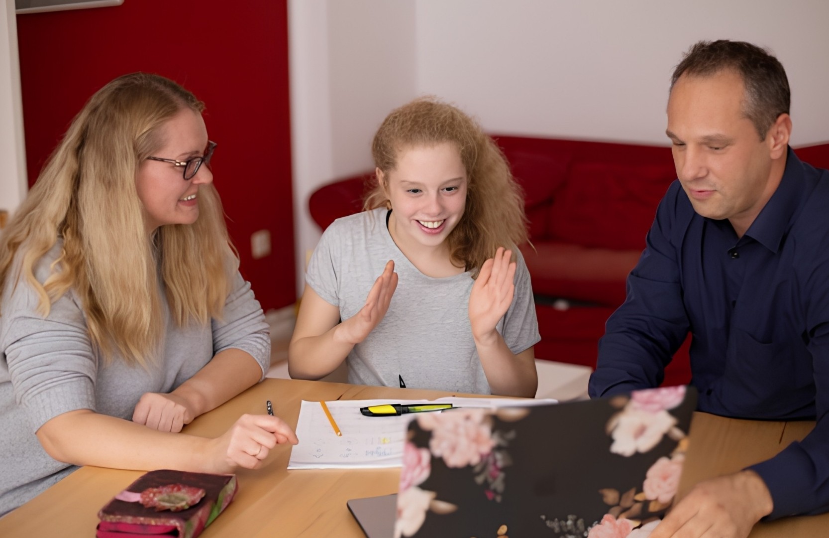 A teenager sat with her parents in front of a laptop