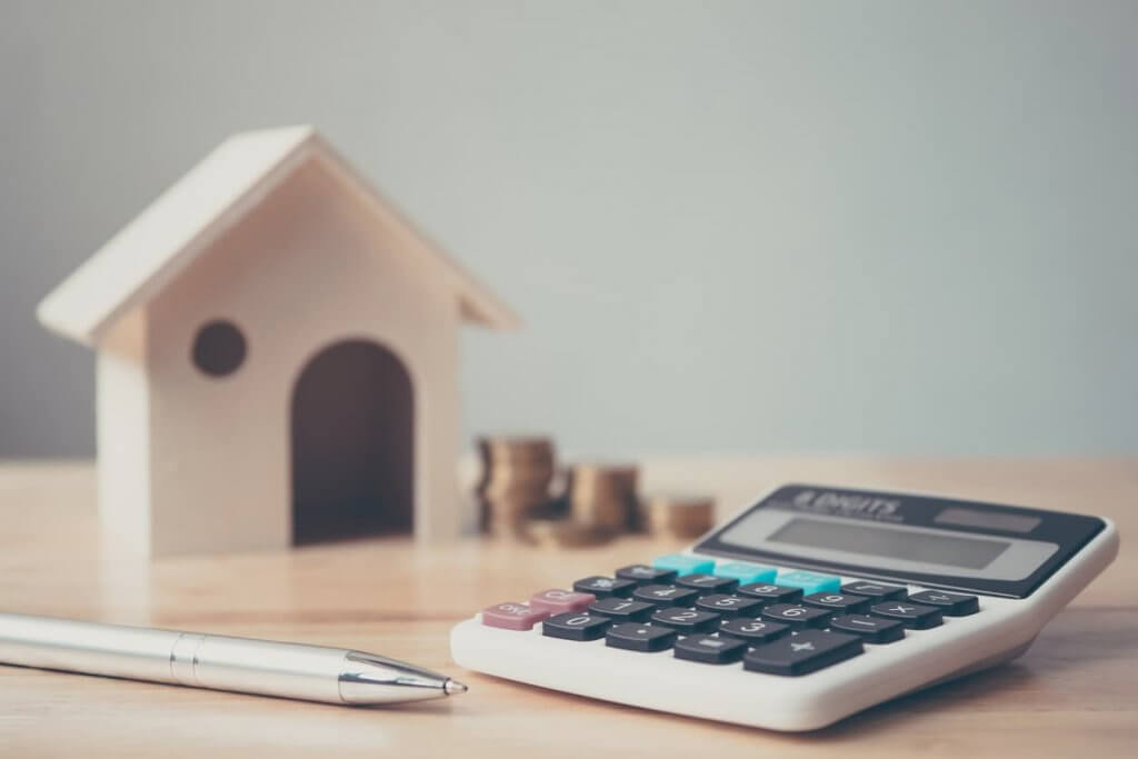 wooden house, pen and calculator