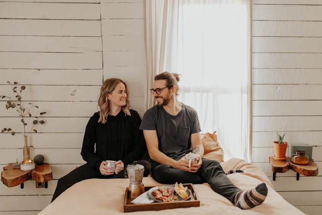 A young couple sitting on the bed of their new home