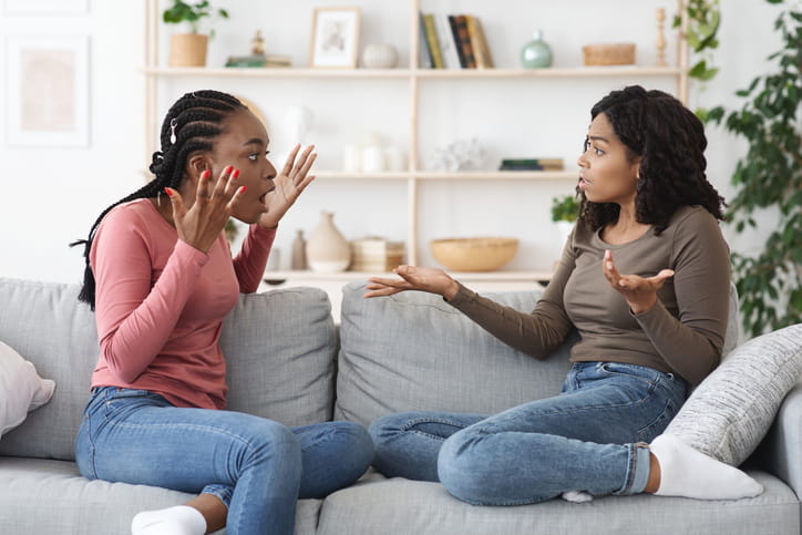 Two female housemates arguing on the sofa