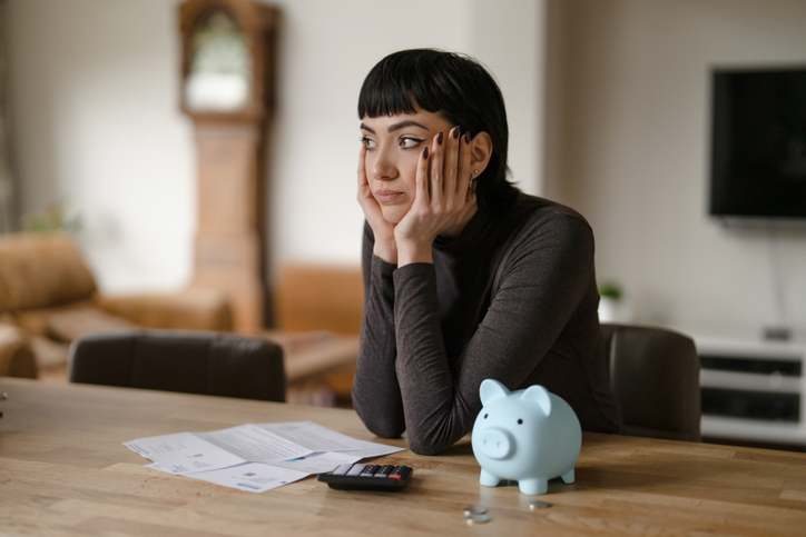 A frustrated student sitting in front of a piggy bank