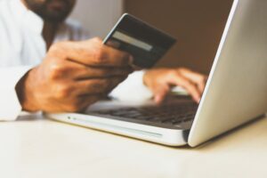 Graduate holding a credit card in front a laptop